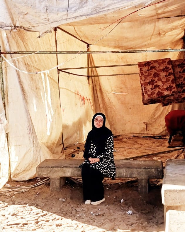 Den palestinske forskaren Asmaa Abusamra under eit telt ved tilfluktsstaden til familien i Rafah. Teltet fungerte som skule om dagen og sovestad om natta.
