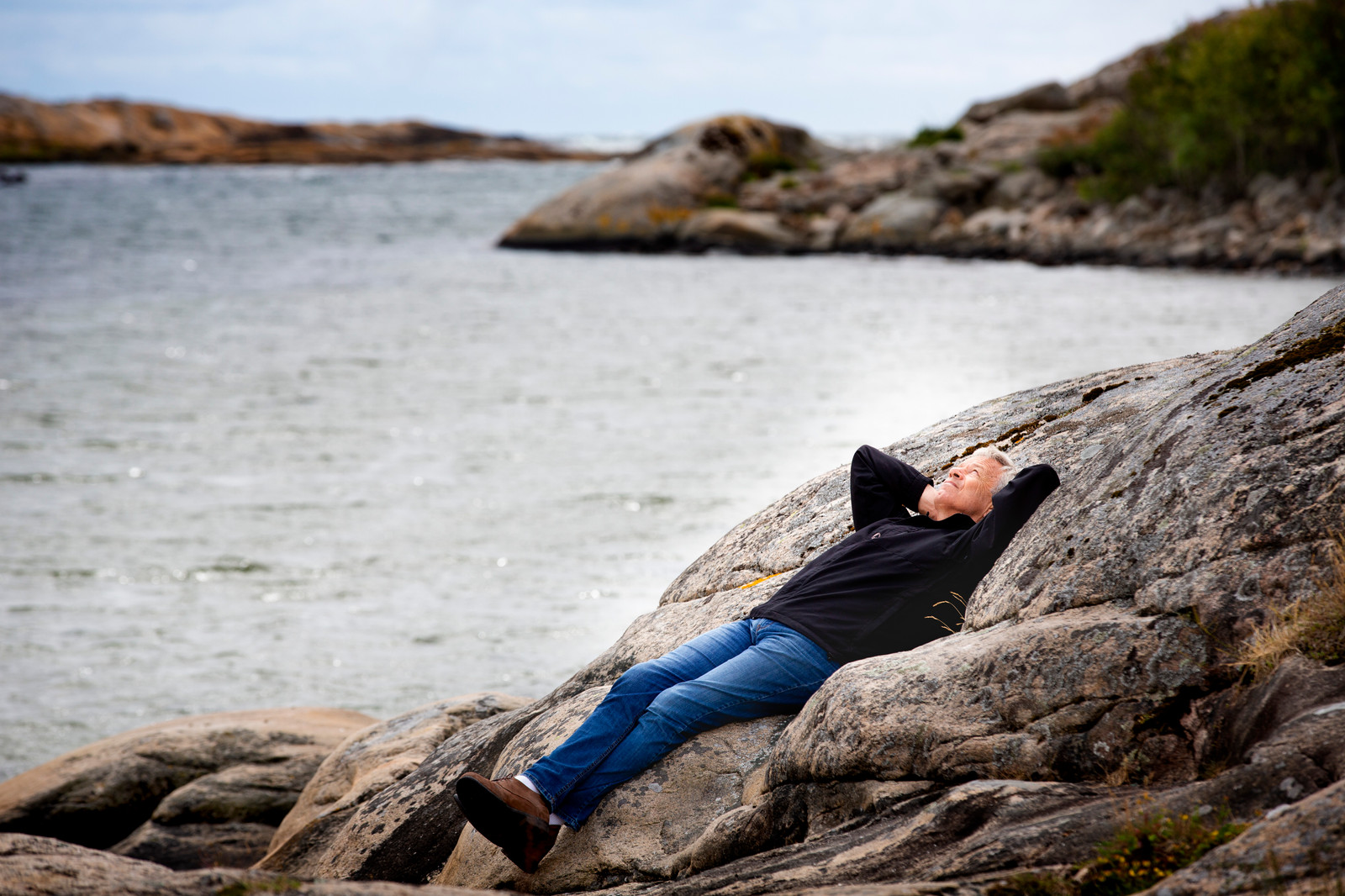 Øystein Olsen ligger på et svaberg.