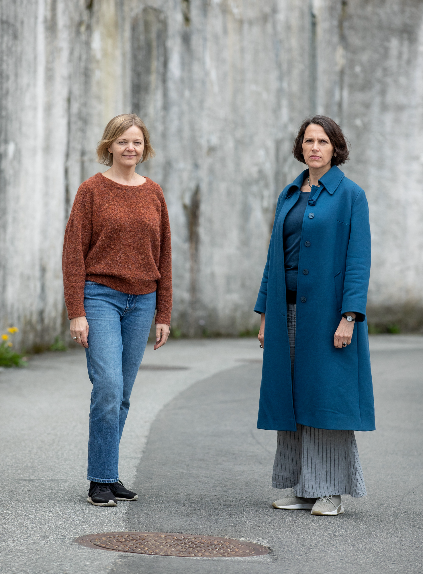 Helfigurportrett av Kjersti Sandvik (til venstre) og Grethe Fatima Syéd (til høyre) utendørs mot grå betongvegg.