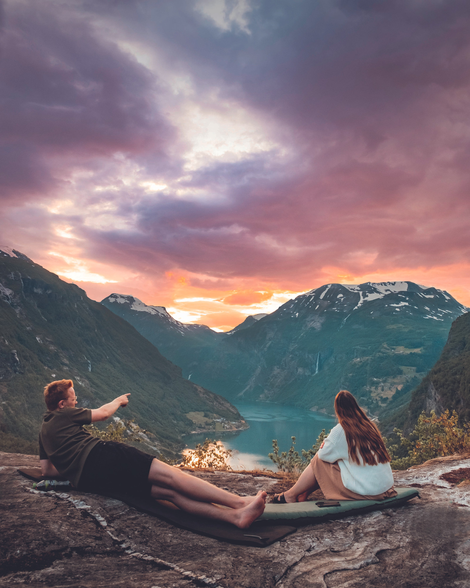 Foto fra boka Tur-retur Norge av Helene Myhre Østervold. Viser et par som sitter med utsikt til fjord og fjelltopper.